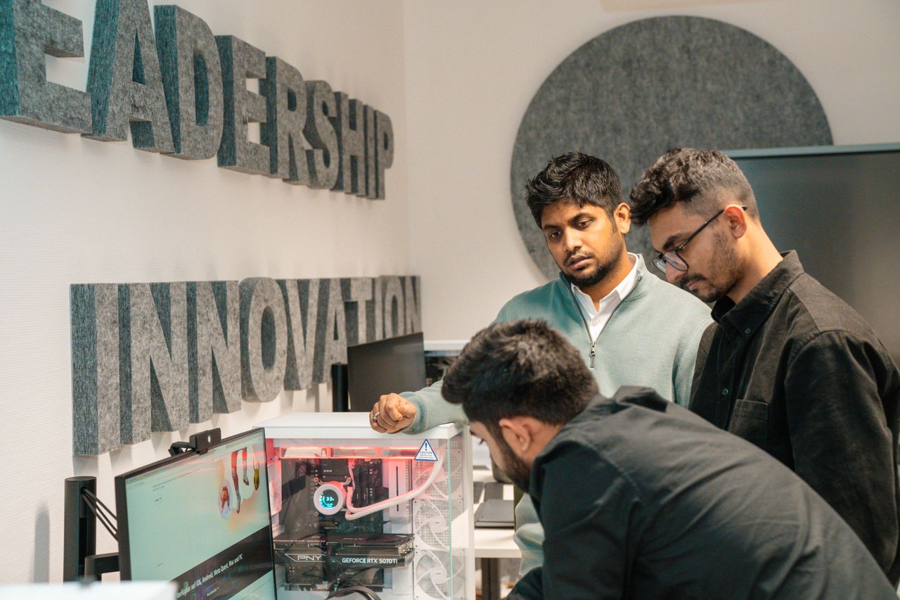Services Three men collaborate in an office, focusing on tech innovation. Leadership and team dynamics emphasized.