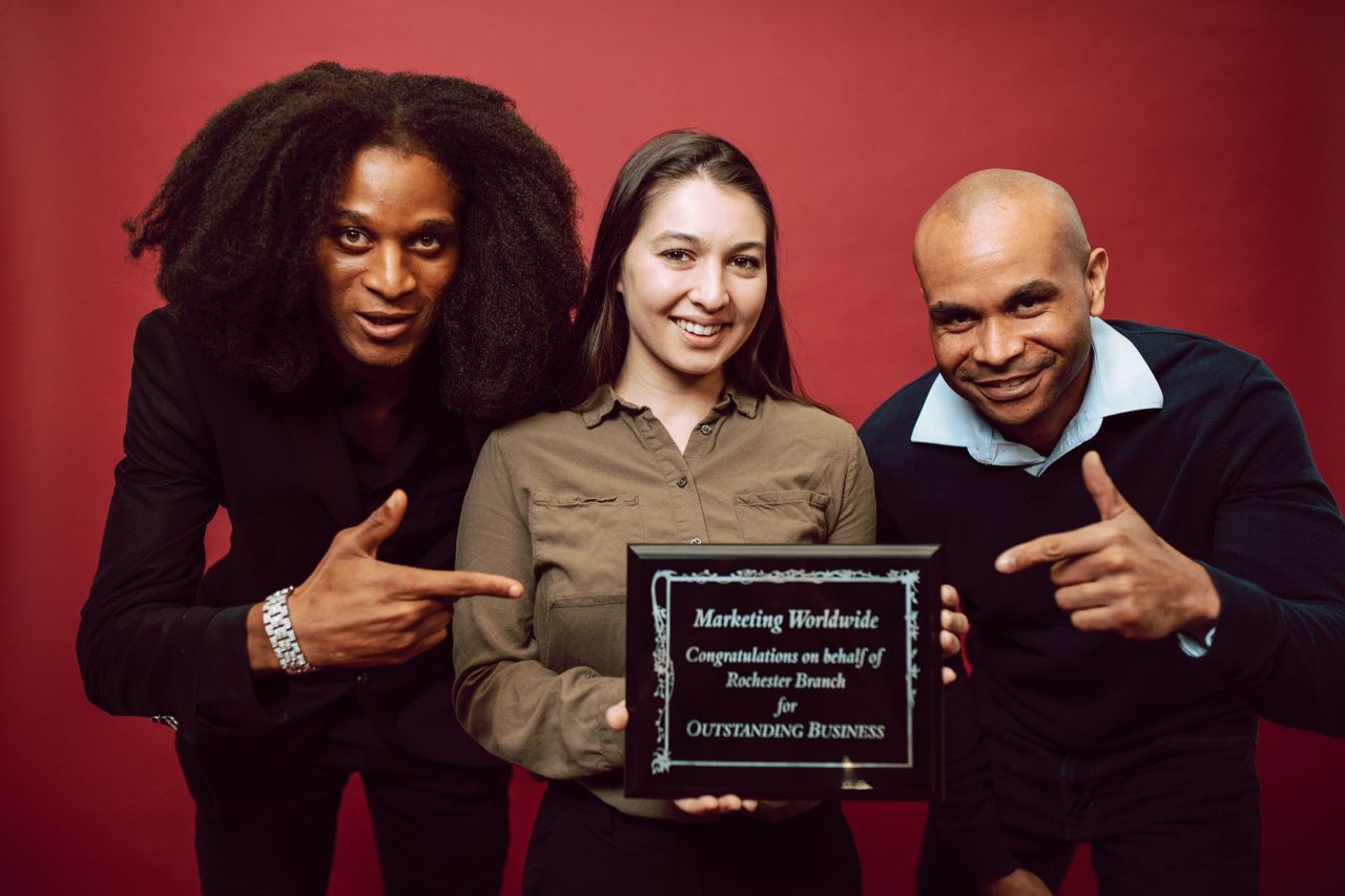 Crafting Captivating Headlines: Your awesome post title goes here Three diverse professionals proudly pose with an award for outstanding business achievement.